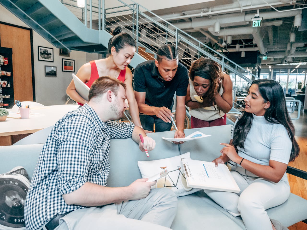 A diverse group of young adults collaborating on a project in a modern office setting.